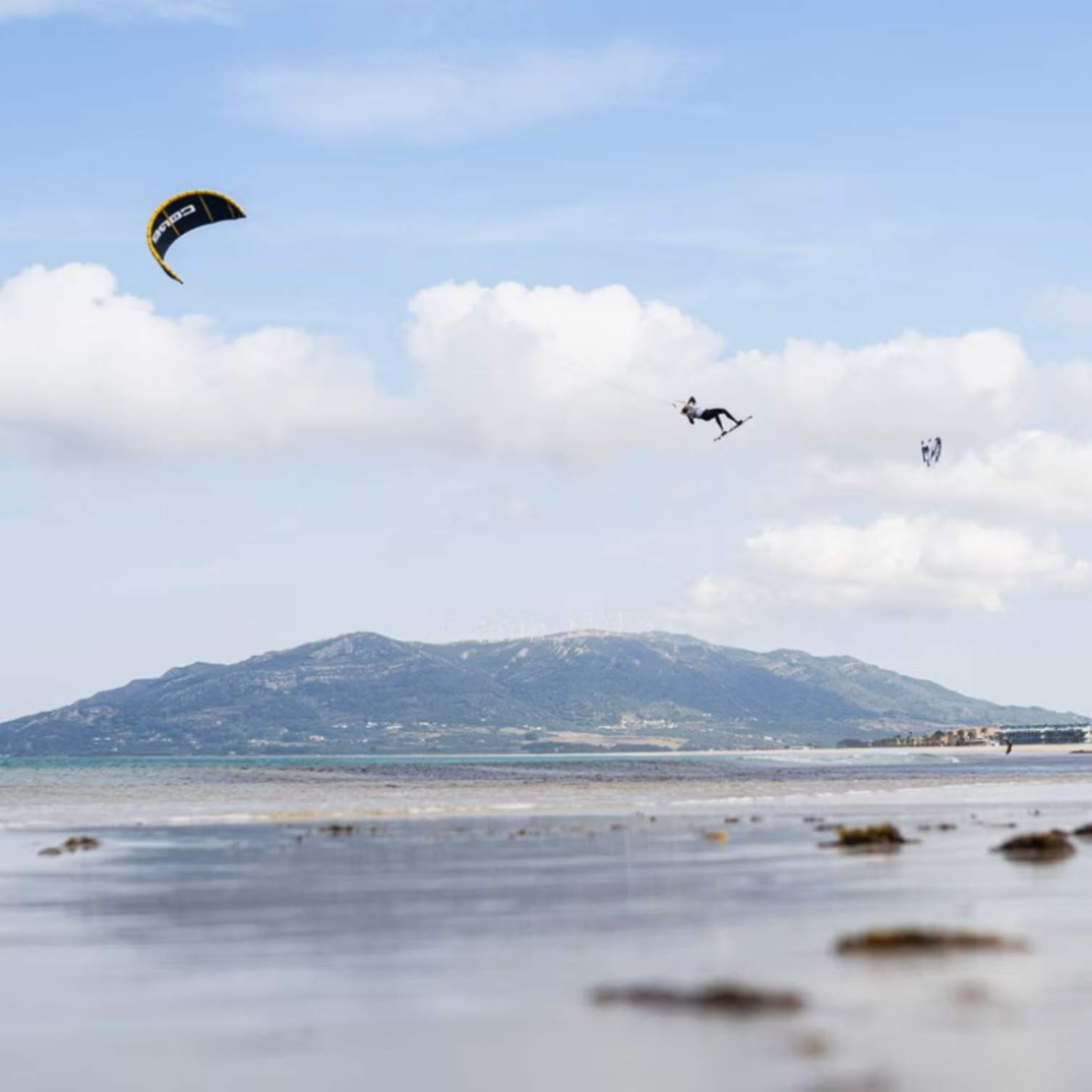 Rideuse effectuant un saut aérien spectaculaire avec l'aile CORE XR PRO sur plage de Tarifa, kitesurf professionnel