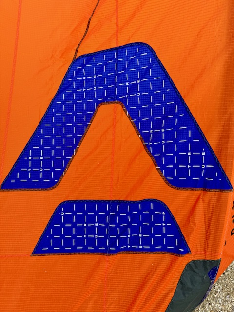 Logo bleu foncé de la marque DUOTONE sur une aile de kite orange.