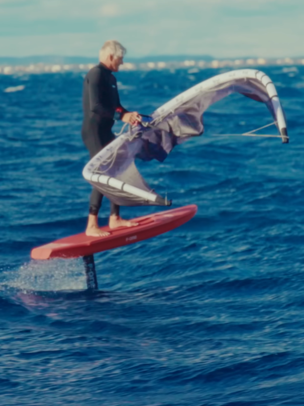 Rider en freefly avec la F-One PLUME 5m² sur foil, aile orange en C-shape stable et légère au-dessus de l’eau.