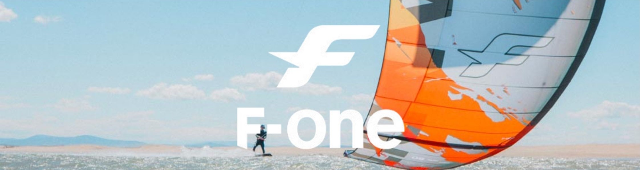 Logo F-One en premier plan avec une aile de kitesurf F-One en arrière-plan
