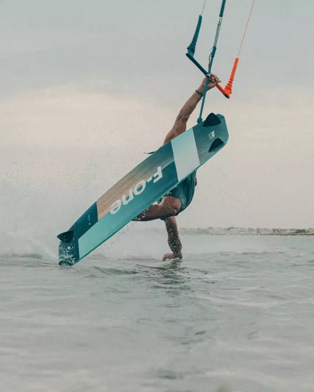 Figure freestyle de kitesurf avec la F-One TRAX 2023, planche en contact avec l’eau pendant un trick engagé